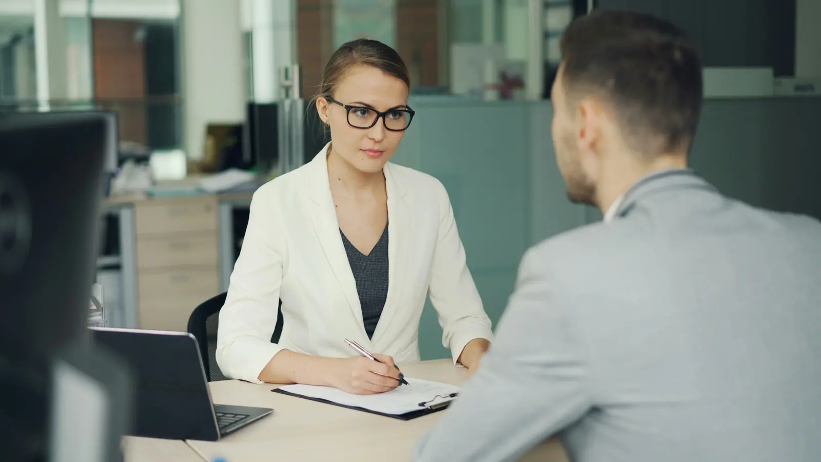 A recruiter interviewing a candidate at an office desk